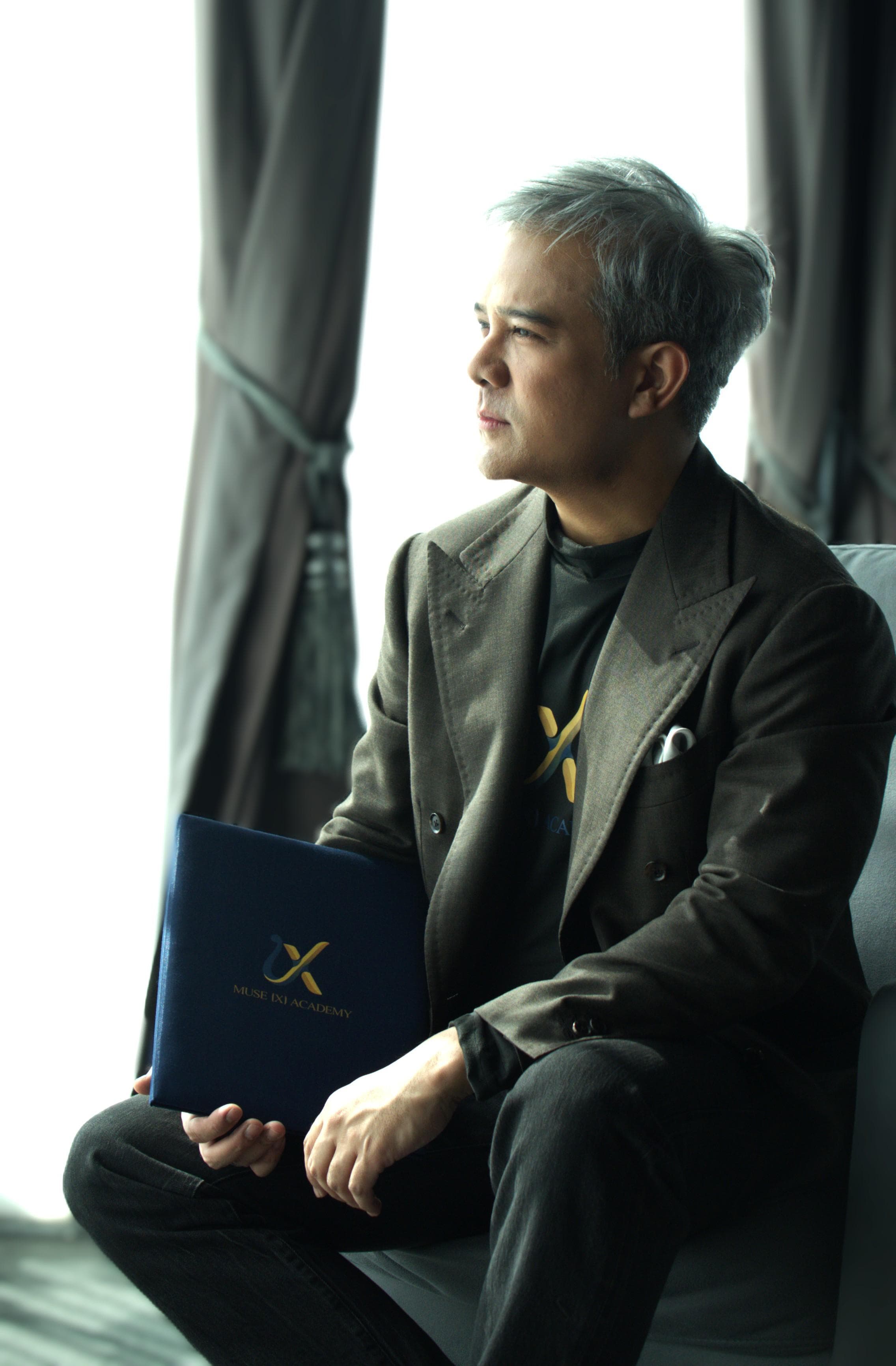 Dr. Akkrawat Paye Srinarong holding a Muse X Academy folder